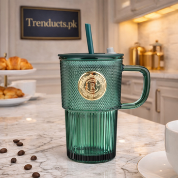 Emerald green textured glass sipper mug with handle, gold crest, and green straw on a wooden background - Trenducts Pakistan
