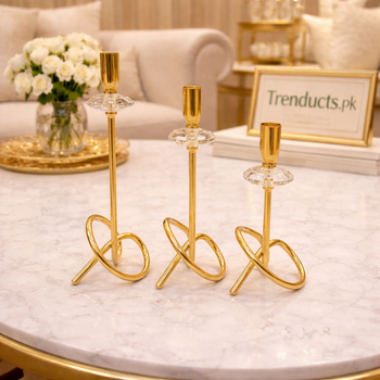 Set of three modern gold metal candle stands with sculptural infinity loop bases and crystal accents in graduated sizes on a white background - Trenducts Pakistan