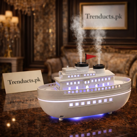 White and black steam ship style aroma diffuser with orange flame mist rising from chimneys on a wooden desk.