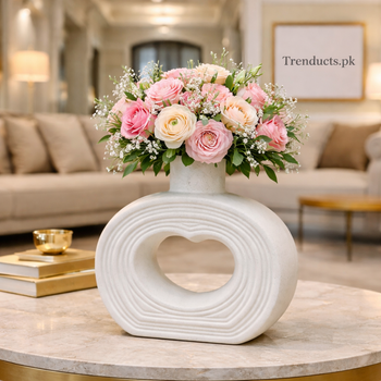 Minimalist textured matte white ceramic flower vase with a central heart-shaped opening, tall neck, displayed on a wooden shelf, suitable for modern Pakistani home decor.