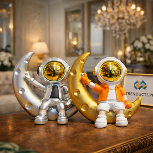 White astronaut sitting on a gold-accented crescent moon showpiece on a modern black desk in a student's room.