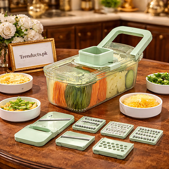 White and green round multifunctional grater with six different blades and a container full of sliced carrots on a marble kitchen counter.
