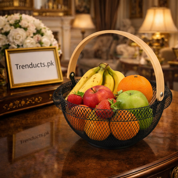 Matte black geometric iron fruit basket filled with oranges on a white marble kitchen island.