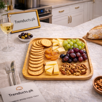 A rectangular bamboo wood food tray with raised edges, sitting on a table with a coffee mug and snacks.