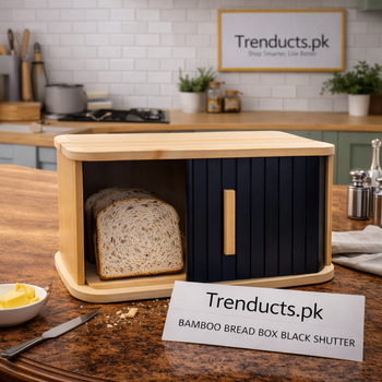 A natural bamboo bread box with a matte black roll-top shutter door on a wooden kitchen countertop.