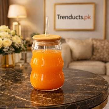 Aesthetic 500ml wavy shaped iced tea glass with bamboo lid and glass straw filled with orange juice on a dark marble table - Trenducts Pakistan