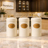 Three off-white metal kitchen canisters with natural rope handles and leather-look labels for Tea, Sugar, and Coffee - Trenducts Pakistan