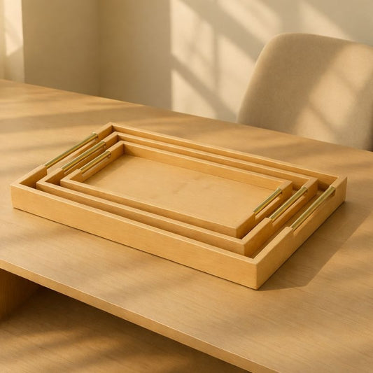 Three nesting rectangular bamboo serving trays with polished golden handles on a light wood table - Trenducts Pakistan