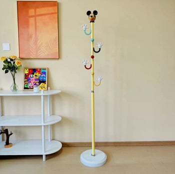A white Mickey Mouse-themed kids' cloth stand with colorful glove hooks in a modern playroom.