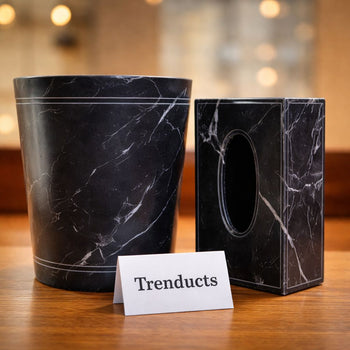 A matching black and white marble-patterned leather waste bin and rectangular tissue box holder on a modern executive desk.