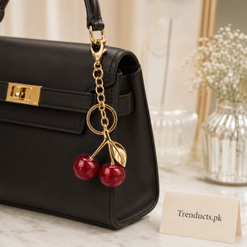 Red cherry keychain attached to a black handbag