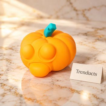 Orange pumpkin bubble-pop fidget on marble studio with Trenducts cream card