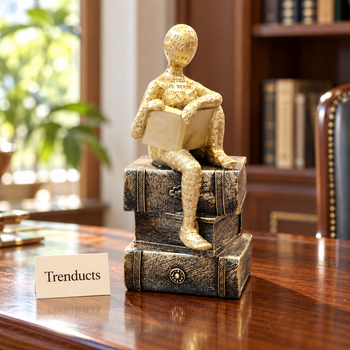 Gold seated reader sculpture on a study table bookshelf | Trenducts
